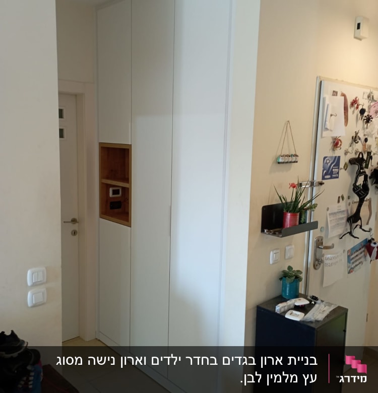 ארון לבן עם דלתות סגורות ומדף עץ קטן